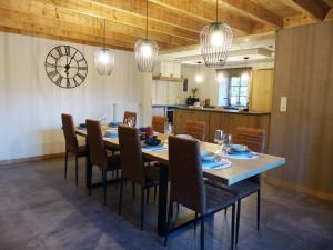 a dining room with a table and chairs and a clock at Le refuge de Julia in La-Roche-en-Ardenne