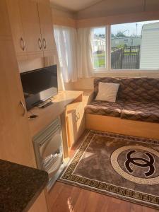 a small living room with a couch and a television at 8 Berth on The Grange (Summer) in Ingoldmells