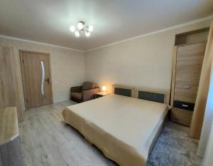 a bedroom with a large white bed and a chair at Апартаменты возле Зоопарка in Kaliningrad