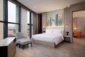 a bedroom with a bed and a desk and a chair at Ramada Encore by Wyndham Dongguan East in Dongguan