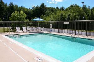 a swimming pool with chairs and an umbrella at Comfort Inn Saco - Old Orchard Beach in Saco