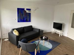 a living room with a black couch and a tv at Strand24 in Ostseebad Nienhagen