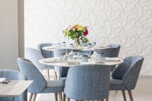einen Tisch mit blauen Stühlen und eine Vase aus Blumen in der Unterkunft Hotel Planamar by Escampa Hotels in Platja  d'Aro