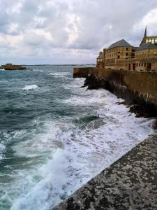 a body of water next to a pier with waves at Au cœur des remparts, L'ÉCRIN Appartement 2 chambres pour 2-6 pers in Saint Malo