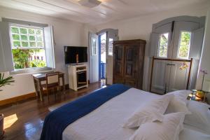 a bedroom with a bed and a tv and windows at Casa Simone Pousada in Paraty