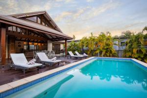 een zwembad met stoelen en een huis bij Indah Port Douglas in Port Douglas