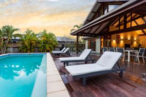une terrasse avec une piscine et des chaises à côté d'une maison dans l'établissement Indah Port Douglas, à Port Douglas