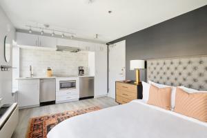 a bedroom with a large white bed and a kitchen at Sonder The Grace in Alexandria