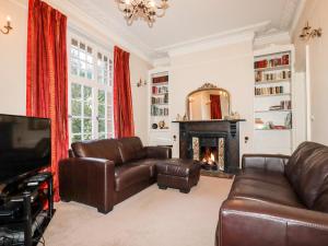 a living room with leather furniture and a fireplace at Lewarne in Boscastle
