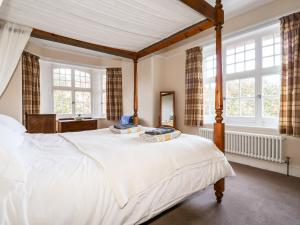 a bedroom with a large white bed with windows at Lewarne in Boscastle