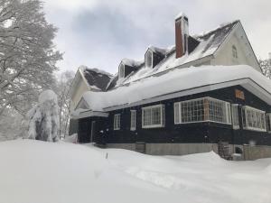 a house covered in snow with a pile of snow at Myoko Forest Lodge in Myoko +150 photos