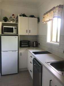 W kuchni znajduje się biała lodówka i kuchenka mikrofalowa. w obiekcie Bryn Glas Farm Stay w mieście Moruya