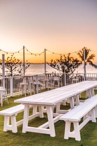 a row of wooden benches sitting on top of a grass covered beach at The Pink Hotel Coolangatta in Gold Coast