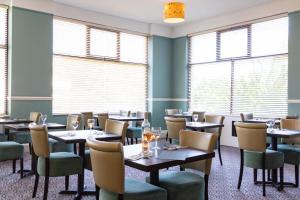 a dining room with tables and chairs and windows at Dilkhusa Grand Hotel by Compass Hospitality in Ilfracombe
