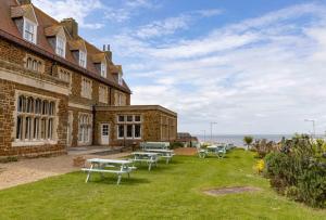 a building with picnic tables in the grass next to the ocean at The Golden Lion Hotel in Hunstanton