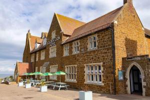 a brick building with tables and umbrellas in front of it at The Golden Lion Hotel in Hunstanton