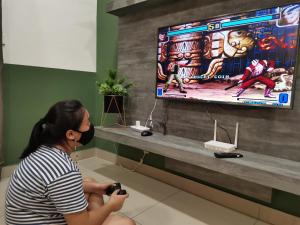 a woman sitting on the floor taking a picture of a video game at HIJAU Geniehome 2BR1studio Free 99mbps WIFI and Carpark at Utropolis Shah Alam in Shah Alam