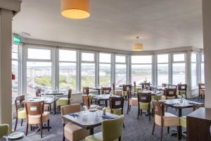 um restaurante com mesas, cadeiras e janelas em The Norbreck Hotel em Scarborough