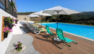 um pátio com cadeiras e um guarda-sol junto a uma piscina em Alqueiturismo - Casas de Campo em Guarda
