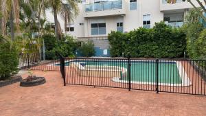 a black fence with a swimming pool in front of a building at Homely Inn Hostel in Gold Coast