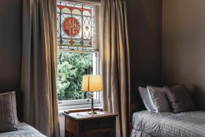 a bedroom with a window with a lamp on a table at Old Bishop's Quarters in Hobart