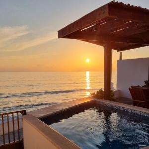 a swimming pool with a view of the ocean at sunset at Villas Bliss 18 in Isla Mujeres