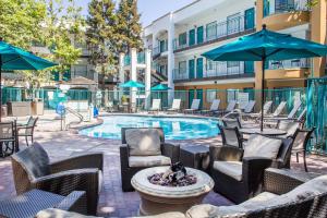 an outdoor patio with chairs and a pool with tables and umbrellas at Quality Suites Downtown San Luis Obispo in San Luis Obispo