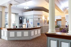a man standing at a counter in a room with columns at The Torbay Hotel in Torquay