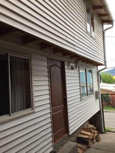 eine Eingangstür eines Hauses mit einer Veranda in der Unterkunft Apartamento Patagonia Dove in Coihaique
