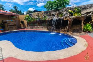una piscina con una cascada junto a una casa en Hotel y Restaurante Las Tablitas, en Alajuela