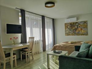 uma sala de estar com uma cama, uma mesa e um sofá em Marių studija em Nida