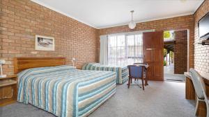 Mooroopna的住宿－Rodney Motor Inn，一间卧室设有两张床和砖墙