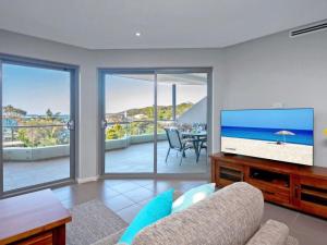 un soggiorno con divano e TV a schermo piatto di Barefoot Bliss 4, 6-10 Market Street - Surfside Apartments a Fingal Bay