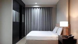 チョンブリーにあるJ Park Hotel - SHA Extra Plusのベッド、ランプ付きのデスクが備わるホテルルームです。