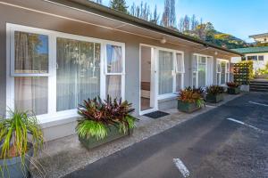 a house with potted plants sitting outside of it at Brookby Motel in Thames