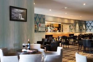 a restaurant with chairs and tables and a bar at The Caledonian Hotel in Fort William