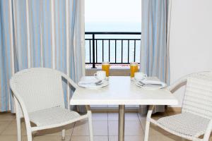 a white table with two chairs and a table with cups at Miramare Hotel in Neos Marmaras