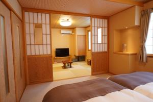 a room with a bed and a television in it at Soumeian in Kusatsu