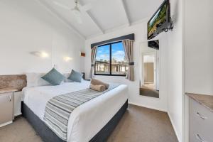 a bedroom with a bed and a tv and a window at Ingenia Holidays Ocean Lake in Bermagui