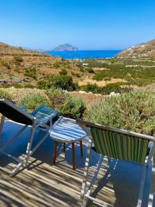 dos sillas y una mesa en un porche con el océano en Villa Handras, 2 unità, en Egíali