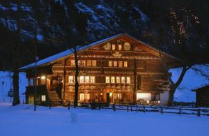 una gran casa de madera en la nieve por la noche en Landgasthof Ruedihus en Kandersteg