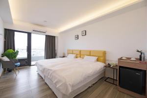 1 dormitorio con 1 cama blanca grande y escritorio en 松柏文旅Cypress Inn, en Taitung