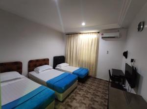 una camera d'albergo con due letti e una televisione di DARUL SALAM INN HOTEL a Kertih