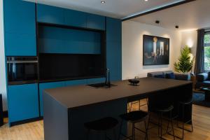 a kitchen with blue cabinets and a bar with stools at JAMES Résidence & Spa in Strasbourg