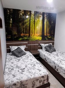 2 Betten in einem Zimmer mit Wandgemälde in der Unterkunft Apartasol, Eje cafetero Reservas de la Colina 111B in La Tebaida