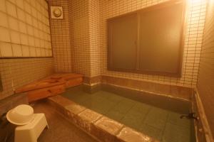 a bathroom with a tub and a toilet in it at Soumeian in Kusatsu