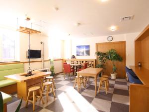 a waiting room with tables and chairs and a tv at Lodge Koropokkuru in Niseko