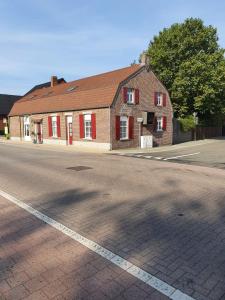 een bakstenen gebouw met rode luiken op een straat bij B&B Le Jardin in Neerpelt