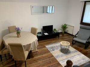 ein Wohnzimmer mit einem Tisch, Stühlen und einem TV in der Unterkunft Bordari by Smiling Rentals in Hondarribia