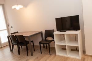 a dining room with a table and chairs and a television at Rossini15 - garage privato in Alba